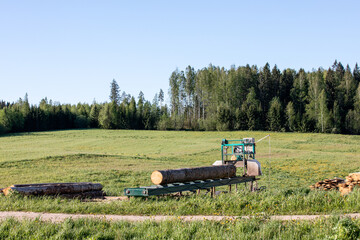 Mobile sawing equipment for logs in the open air. Rural landscape on a sunny day