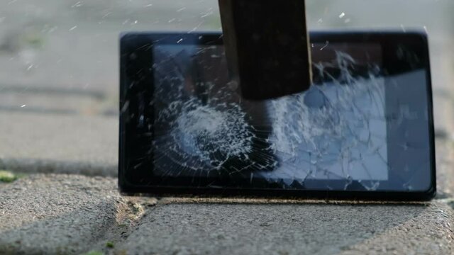 Hammer smashing smartphone, closeup, slow motion