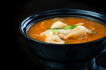 Japanese Soup With Chicken, Egg, Simeji Mushrooms and Eggplant On a Dark Background in a black plate. close up