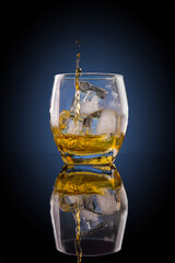 Whisky ice glass with reflection on dark background. 