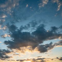 Fototapeta premium sun sets behind the clouds in the blue evening sky as a natural background