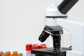 Microscope and test tubes on table in laboratory, close up