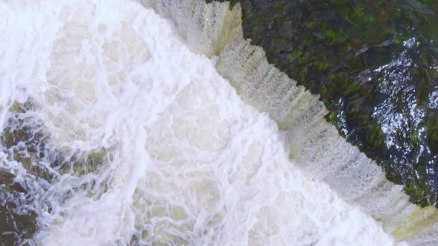 Top view close up of waterfall splashes with fish jumping up, day