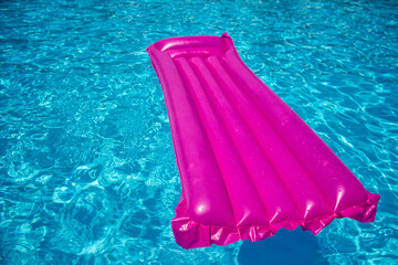 Pink air mattress on a swimming pool, tropical background concept.