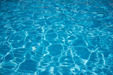 Blue and bright water in swimming pool with sun reflection. Motion of ripple water in pool.