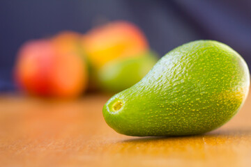 Avocado fuerte with fruits on the background, avocado in front of fruits horizontal photo natural light, healthy fruits on background