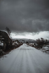 Straight snowy road leading to norwegian mountains, vertical photo