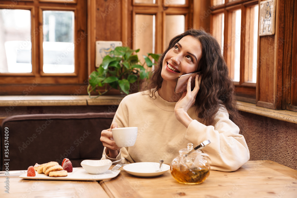 Canvas Prints Image of joyful woman talking on cellphone while having breakfast