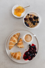 Healthy breakfast concept. Granola with coffee, berries, croissants and orange marmelade.