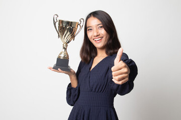 Successful young asian woman holding a trophy show thumb up.