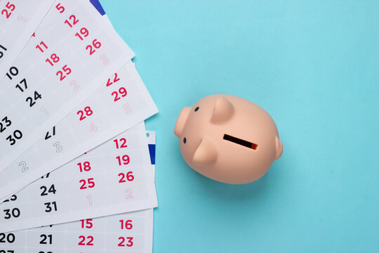 Piggy Bank With A Monthly Calendar On A Blue Background. Payment Of Rental Housing Or Loans. Top View