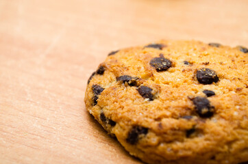 Cookies on a wooden table in macro. Shortbread orange cookies with chocolate chips, pieces of chocolate in a very strong large approximation. Cookies on a wooden table in the lower right