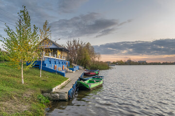 Evening landscape near the water with a beautiful sunset and boats near the pier in the...
