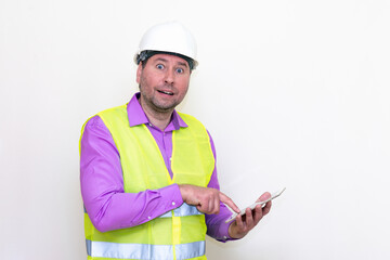 Construction builder wearing helmet yellow protective vest using wireless tablet and showing like or thumbs-up shocked poke up shows to you and victory  gesture isolated on white background.