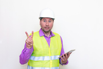 Construction builder wearing helmet yellow protective vest using wireless tablet and showing like or thumbs-up shocked poke up shows to you and victory  gesture isolated on white background.