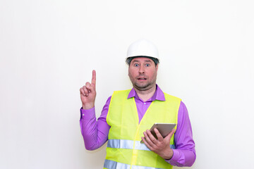 Construction builder wearing helmet yellow protective vest using wireless tablet and showing like or thumbs-up shocked poke up shows to you and victory  gesture isolated on white background.