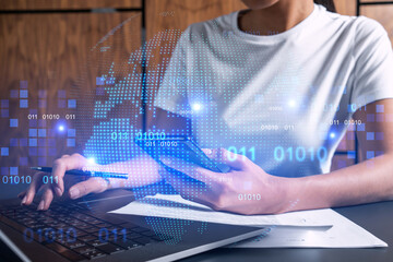 Businesswoman typing on laptop in office. Planet earth world map hologram. International business concept. Double exposure.