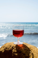 Rosé wine in a glass with the beach and the sea in the background