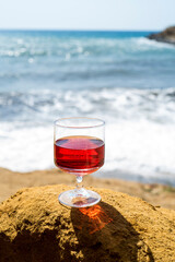 Rosé wine in a glass with the beach and the sea in the background