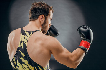 Plakat A man in Boxing gloves. A man Boxing on a black background. The concept of a healthy lifestyle