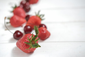fresh summer berries on a white wooden table. strawberries and cherry, close up view. copy space for text or advertising. selective focus