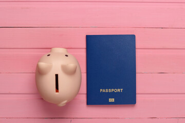 Travel or emigration. Passport with piggy bank on pink wooden background. Top view