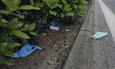 Mascarilla de papel y guantes de látex tirados en una carretera urbana. Residuos sanitarios...