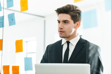 Image of concentrated young businessman using laptop while working