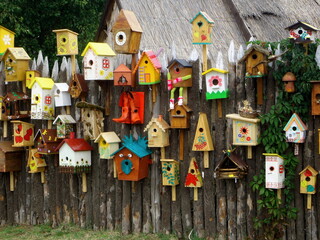 Many different shapes bird feeders birdhouse for nesting box hanging on wooden fence. Bird feeders...
