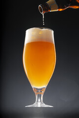 Beer pouring into glass on black background