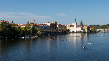 Fototapeta na wymiar View of Prague from the bank of the Vltava. Tourists in boats on the river.