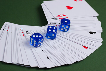 Dice with playing cards on a green background. Gaming addiction, poker, casino