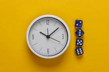 Good luck time. White clock with dice on yellow background. Top view. Flat lay