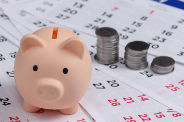 Piggy bank and stack of coins on monthly calendar, saving money, wealth and financial for investment