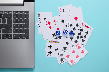Playing Cards and Blue Dice, laptop keyboard on blue background. Online poker casino. Top view