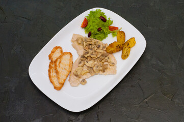 Stewed mushrooms with fish fillet, salad, fried potatoes and croutons, on a warm gray background....