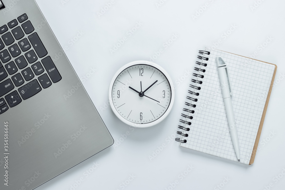 Poster laptop, notebook and alarm clock on white background. the concept of urgent deadlines at work and co