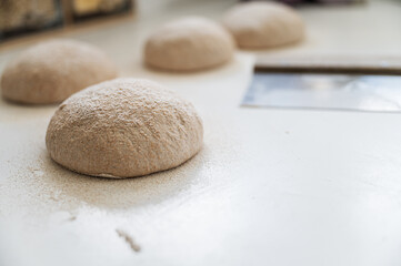Fototapeta na wymiar Fresh dough for bread buns resting and rising on kitchen counter