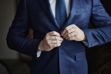 Businessman wears a jacket, male hands closeup,groom getting ready in the morning before wedding...
