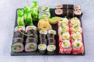 Sushi Set sashimi and sushi rolls served on stone slate