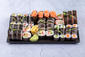 Sushi Set sashimi and sushi rolls served on stone slate