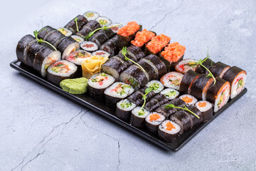 Sushi Set sashimi and sushi rolls served on stone slate