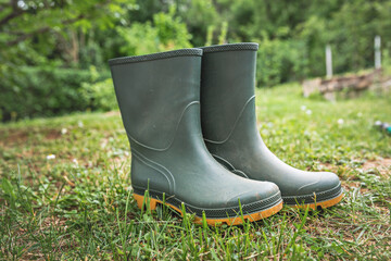Green, gardening boots made of rubber, inside the garden.