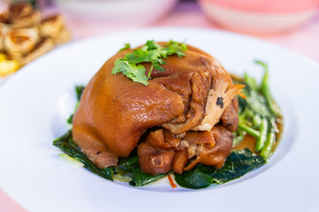Stewed pork leg with kale on a white plate.