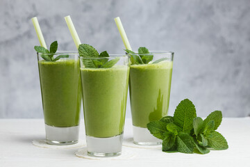 Freshly blended green fruit smoothie in glass.