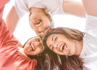 Best friends take a selfie from below with smartphone on vacation - group of happy multiracial tourists taking a funny photo - friendship and fun concept.