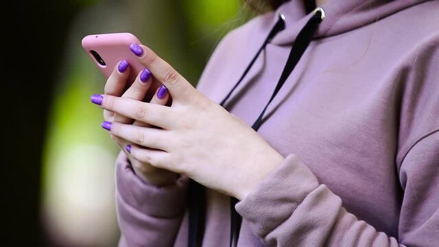  Young woman using mobile smart phone in the park during spring or summer. Internet, using smartphone, close-up fashion model, post in instagram, facebook concept