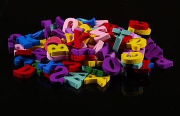 Fototapeta premium Many colored wooden letters isolated on black background.