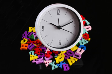 White clock with colored letters on a black background