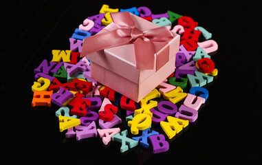 Gift box with colored letters on a black background